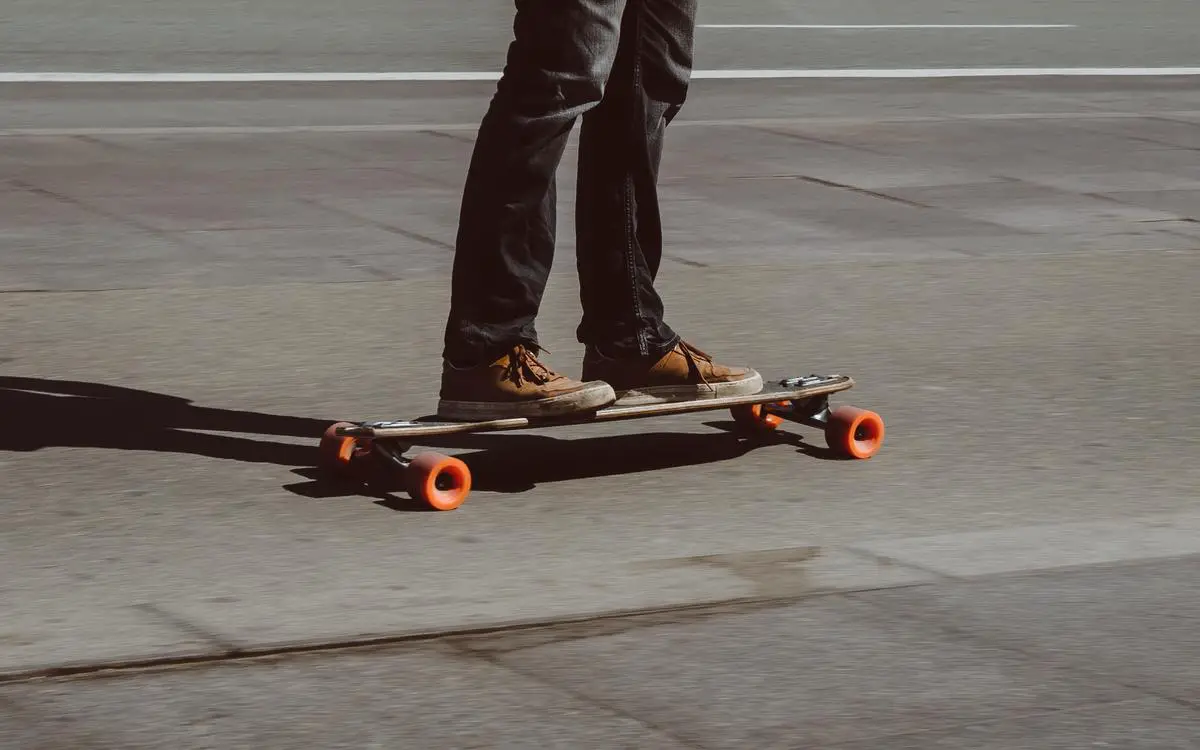 A person riding an electric skateboard with a city skyline in the background.