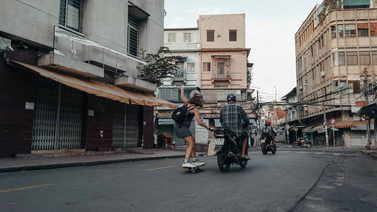 An image of a dual motor electric skateboard showing a rider cruising through the city.