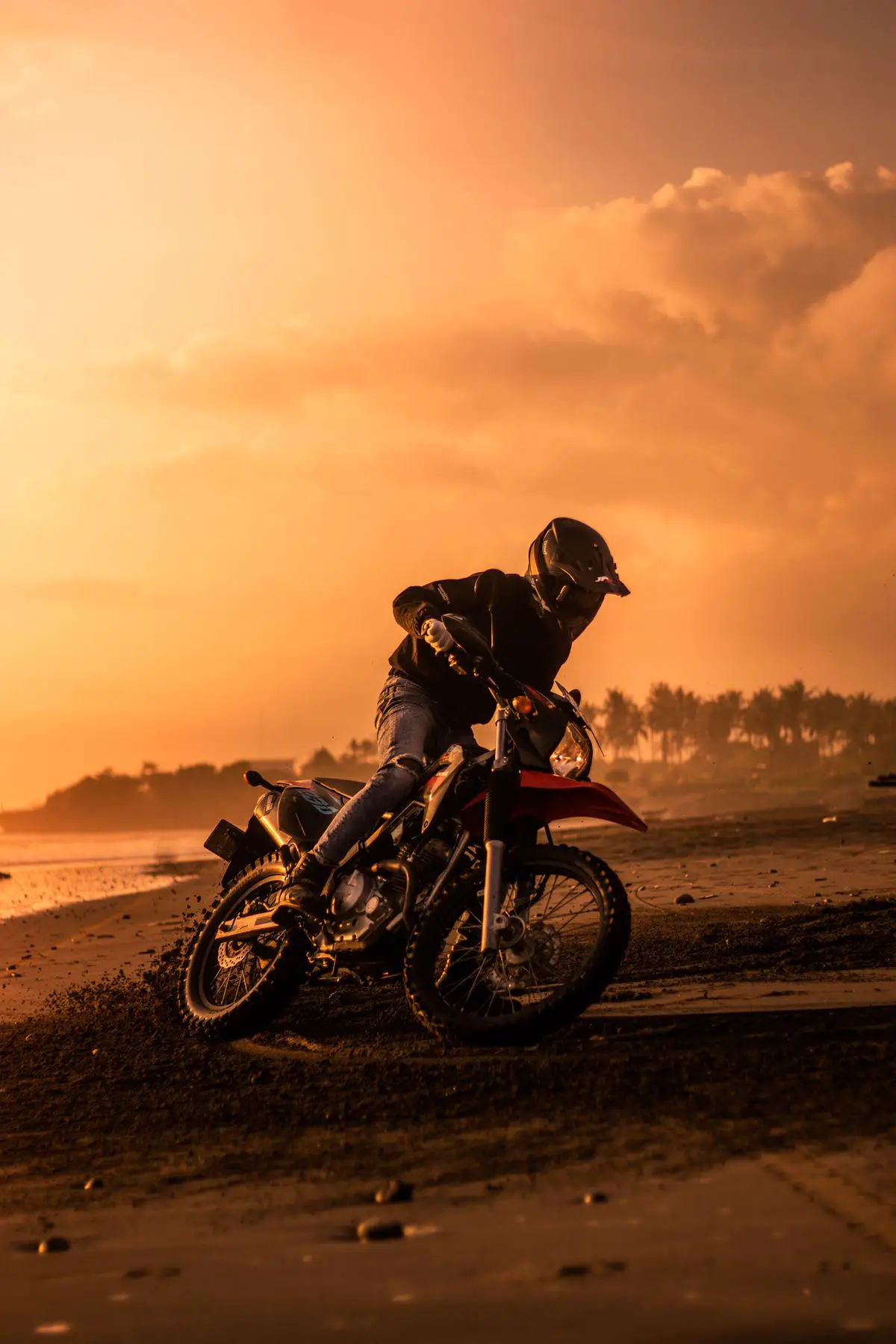 A serene image of a rider on an e-bike cruising along a beach with the sun setting in the background.